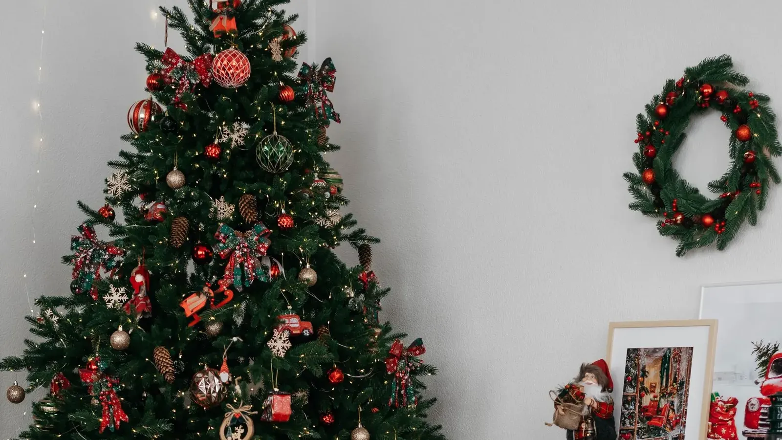 Christmas tree with red baubles and plaid ribbons beside a white mantel, wreath and a red wooden rocking moose